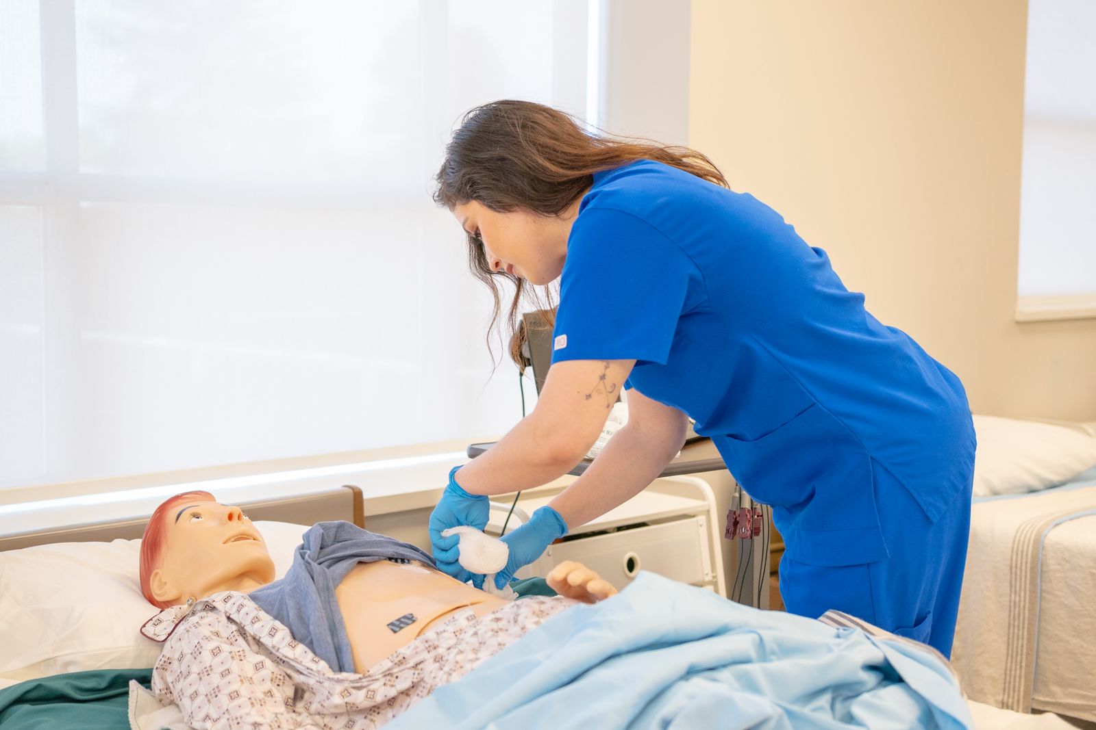 Nursing student practising patient care on a training manikin